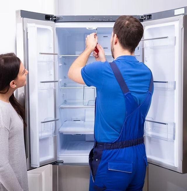 Técnico realizando manutenção em geladeira na residência do cliente